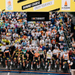 Peloton regroupé sous l'arche de départ de l'Etape du Tour 2025