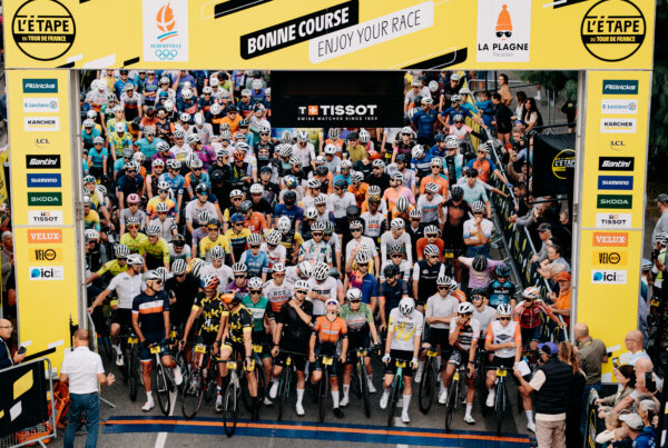 Peloton regroupé sous l'arche de départ de l'Etape du Tour 2025