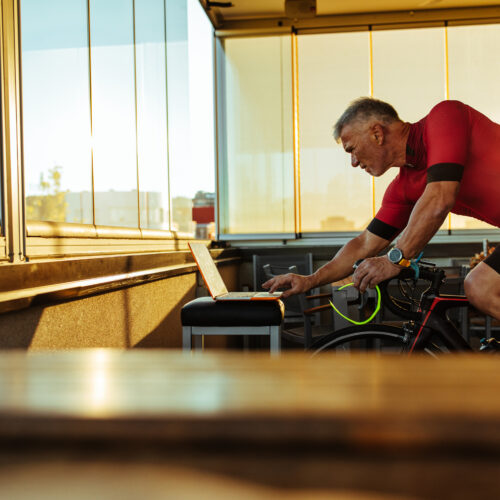 homme sur home trainer lance une sortie virtuelle sur son ordinateur