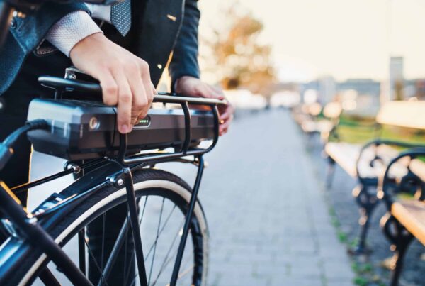 homme en costard mettant en place sa batterie de vélo électrique sur le porte bagage